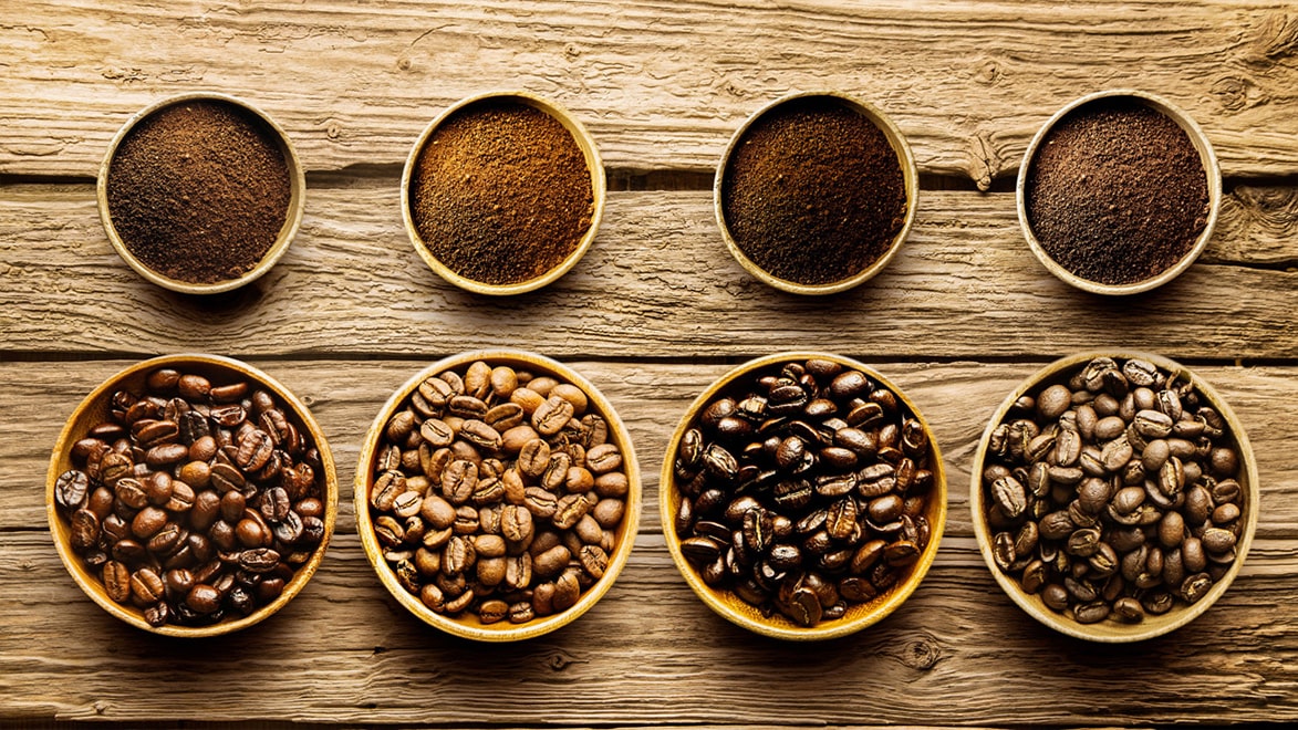 A warm, inviting kitchen scene featuring a steaming cup of coffee, a bag of whole bean coffee, a manual grinder, and scattered beans on a rustic countertop, with an Irish countryside visible through the window in the background.