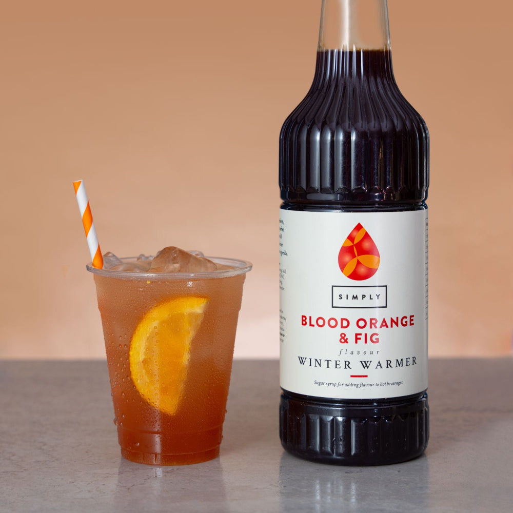 Lifestyle photo plastic cup iced blood orange fig winter warmer drink orange slice straw beside Simply syrup bottle