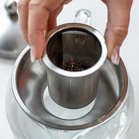 Hot water being poured from electric kettle into green mug during tea brewing