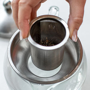 Hot water being poured from electric kettle into green mug during tea brewing