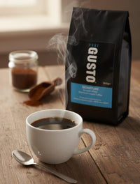 Steaming cup of coffee with spoon on wooden table next to Pure Gusto Signature 300g instant coffee bag and jar of grounds