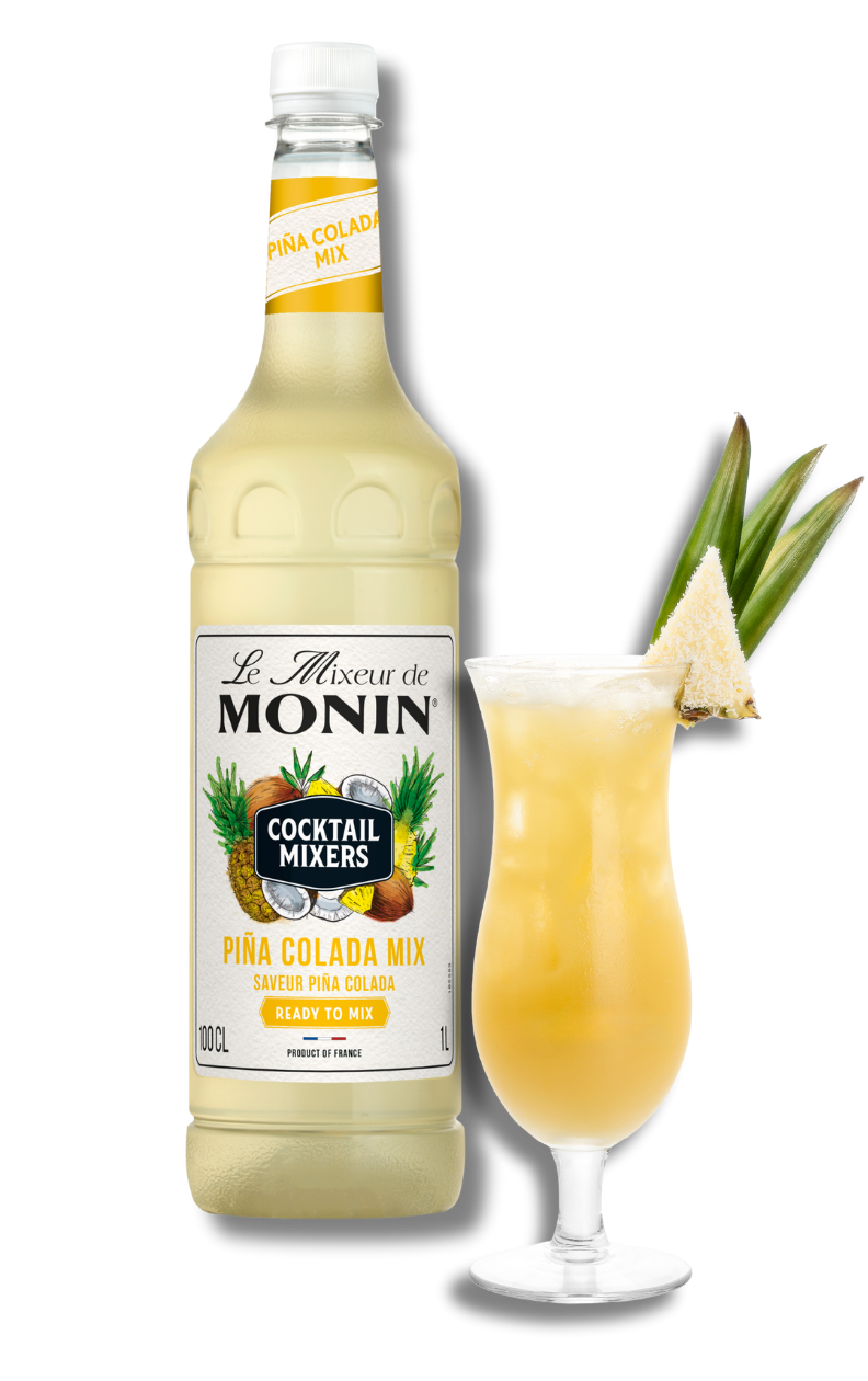 Monin Pina Colada Mix bottle with a glass of cocktail and pineapple garnish on a white background