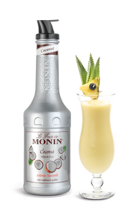 A bottle of Monin Coconut Puree with a decorative glass of coconut drink garnished with a pineapple slice and coconut on top.