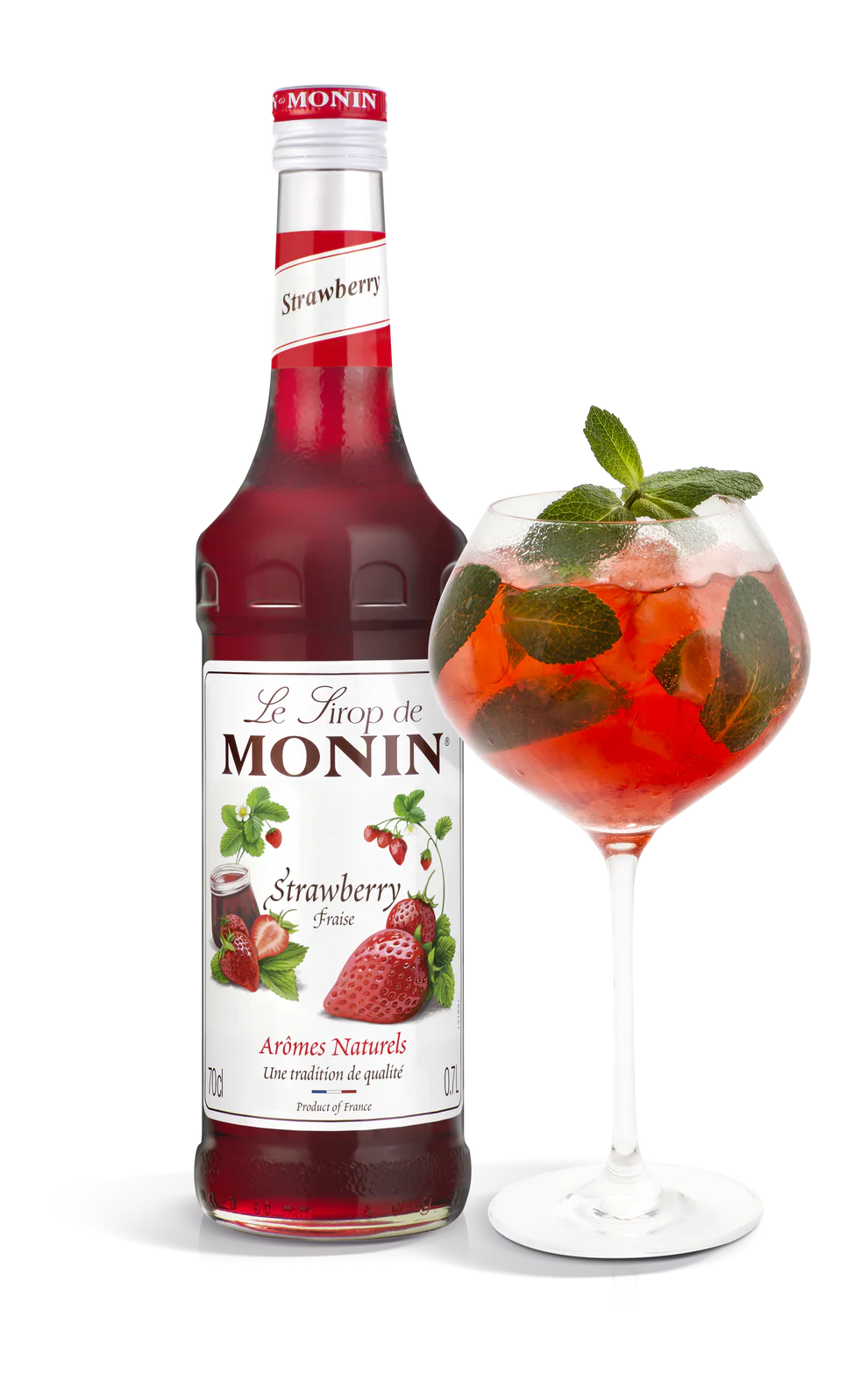 Monin strawberry syrup bottle with a glass of strawberry cocktail on a white background