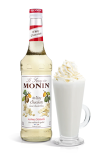 Monin white chocolate syrup bottle with a glass of white chocolate latte on a white background