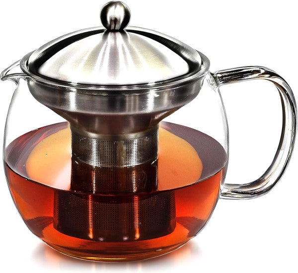 Hands placing loose leaf tea into stainless steel infuser over glass teapot