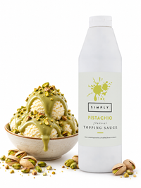 A bottle of Simply Pistachio flavour Topping Sauce stands next to a bowl of vanilla ice cream drizzled with the green pistachio sauce and topped with chopped pistachios, with scattered pistachio shells on a white background.