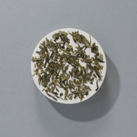 Suki Organic Sencha loose green tea leaves on a white plate