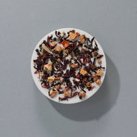 Suki Red Berry loose leaf fruit tea with hibiscus, apple, rosehip and elderberries on a white plate
