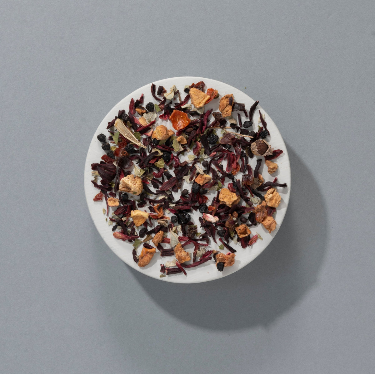 Suki Red Berry loose leaf fruit tea with hibiscus, apple, rosehip and elderberries on a white plate
